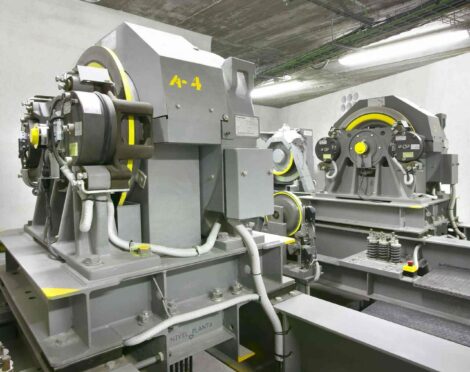 Elevator machinery room with large industrial machines, motors, and cables.