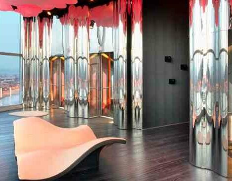 Futuristic interior with glass elevators, metallic columns, and a city view.