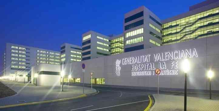 Exterior view of a modern hospital at night, with illuminated windows and a curved road in the foreground.
