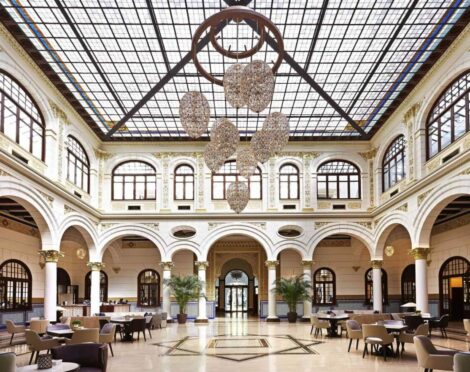 A luxurious hall with arched windows, marble floors, and a grand chandelier.