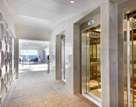 Modern elevator lobby with marble walls and open elevators.
