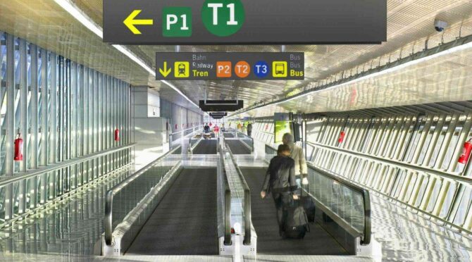 Airport terminal with signs directing to terminals, parking, and transportation.