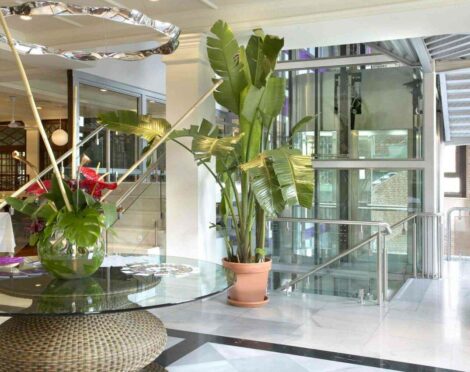 Lobby with glass elevator and tropical decor.