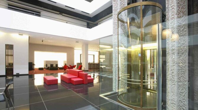 Spacious, modern interior with red seating, a glass elevator, and polished black flooring.