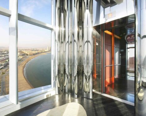 High-rise building interior with panoramic coastal city views, showcasing the beach, sea, and skyline.